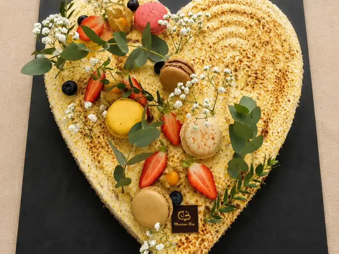 Gâteau d'événement en forme de cœur garni de fruits et macarons