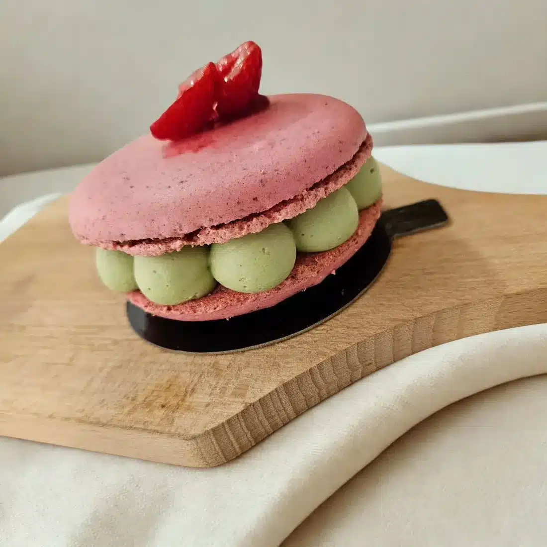 Macaron framboise et pistache sur planche en bois
